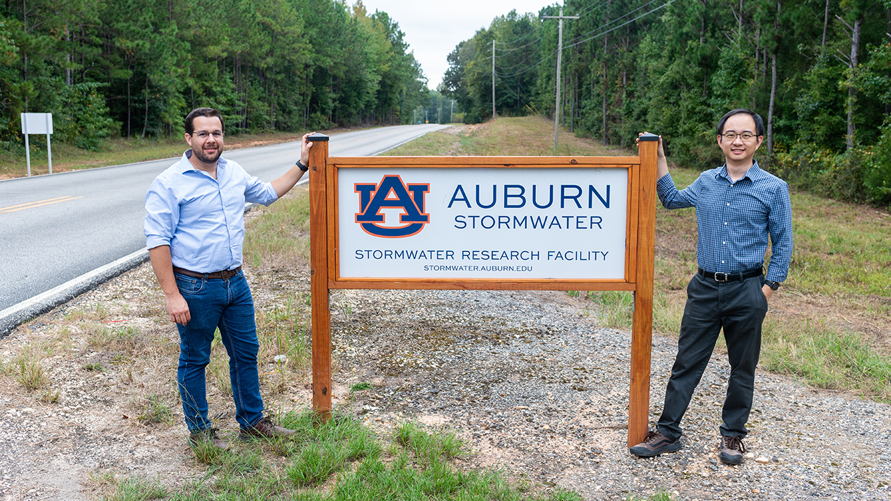 two men stand next to sign