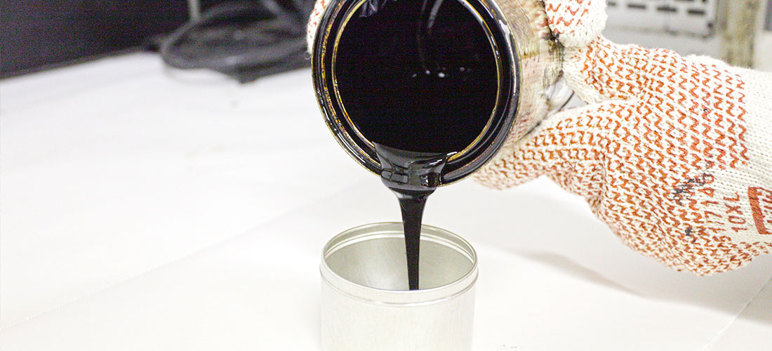 Liquid asphalt binder being poured by lab technician