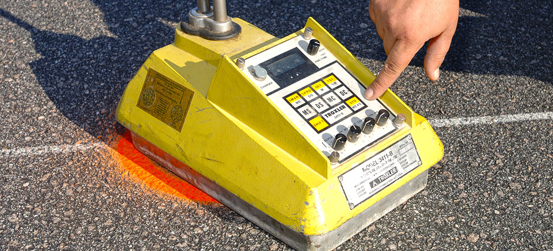 Person pressing button on Asphalt Density Gauge