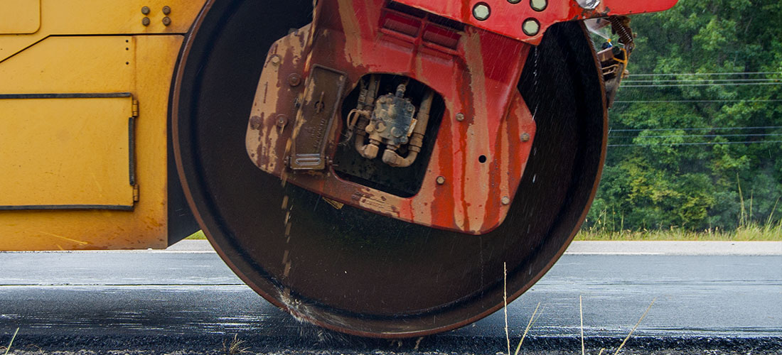 Steamroller passing over freshly paved surface