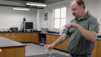 Lab manager Jason Moore walks through one of NCAT's laboratories, where experiments are performed on bits of pavement to see how they handle various weather and traffic conditions. National Center for Asphalt Technology.