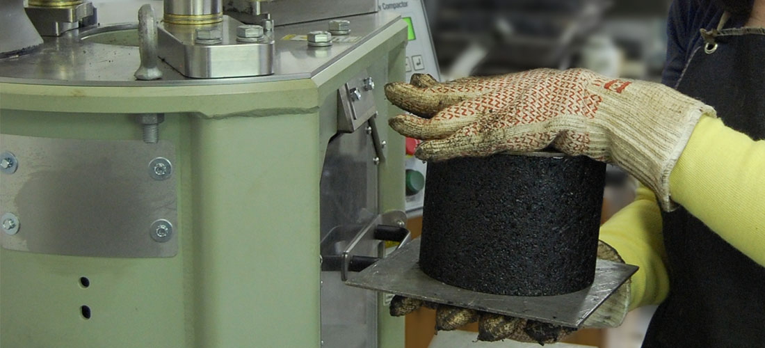 Lab technician removing compacted sample from gyratory device